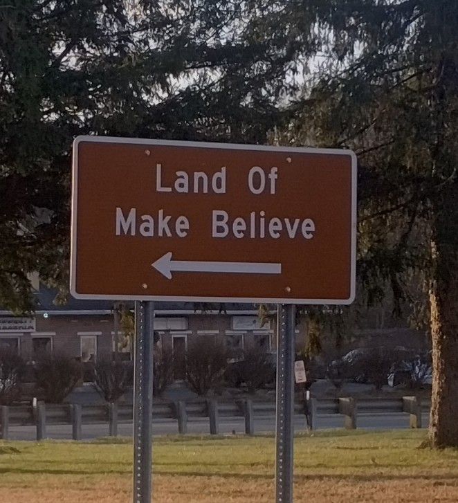 Brown sign that says "land of make believe"