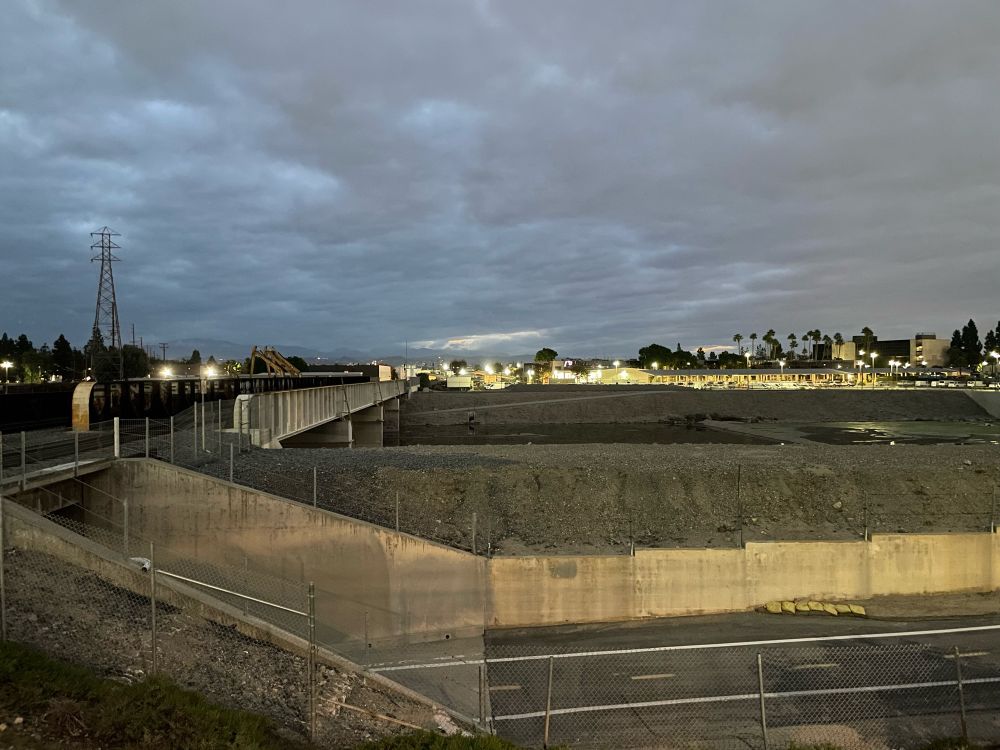 Train tracks, a road underpass, and the city of Orange, CA. Is this the first little bit of sunlight peaking out?