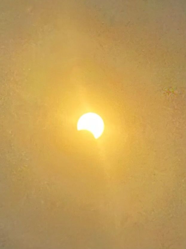 Direct photo of the sun, via a filter. The background is bright and it shows a very small 1/8 notch of moon.