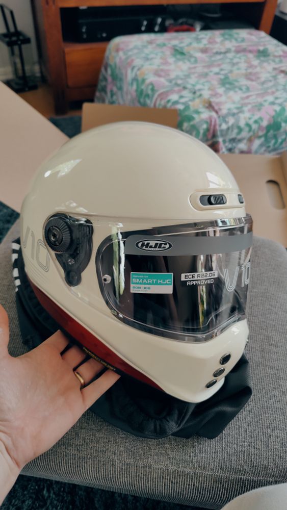 A white HJC V10 Tami motorcycle helmet with red accents