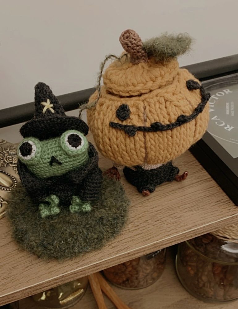 A crochet frog and a crochet pumpkin jar on the shelf. 