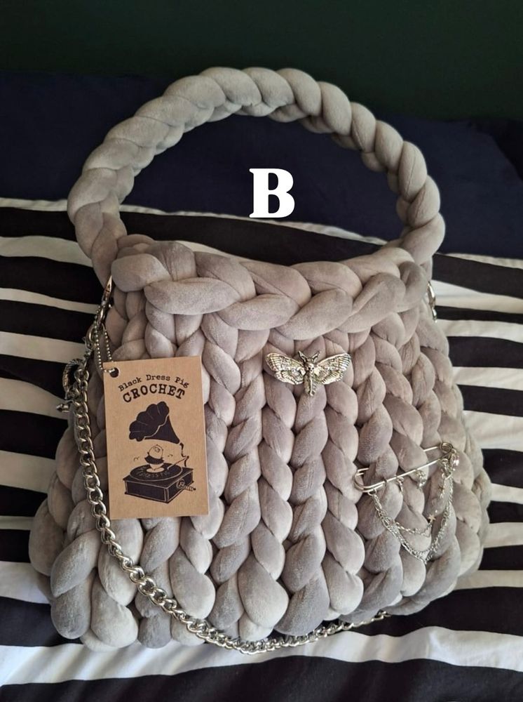 A silver hand knit/crochet bag made of chunky yarn with accessories. 