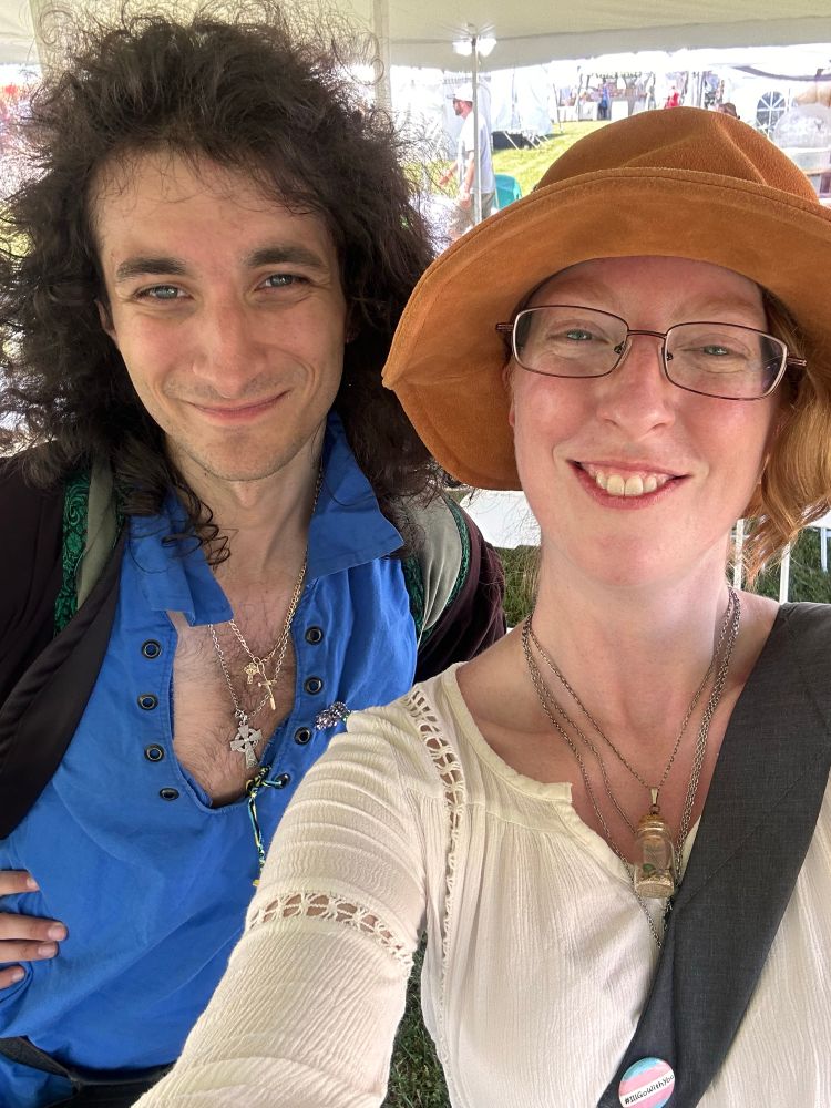 A selfie of a nonbinary woman and a curly haired magician. 