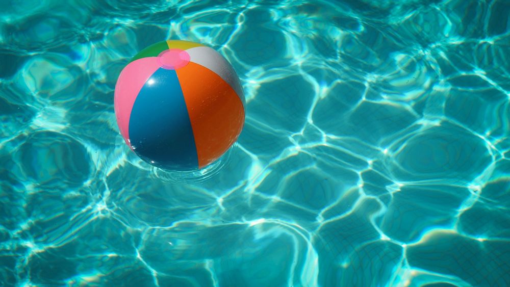 A beach ball floating on a sunlit pool