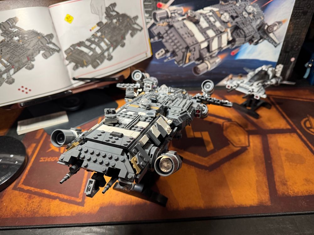 In the foreground the completed Onyx Cinder LEGO model is on a stand making it look like it is taking off toward the camera. In the background is a LEGO pirate fighter in pursuit.
