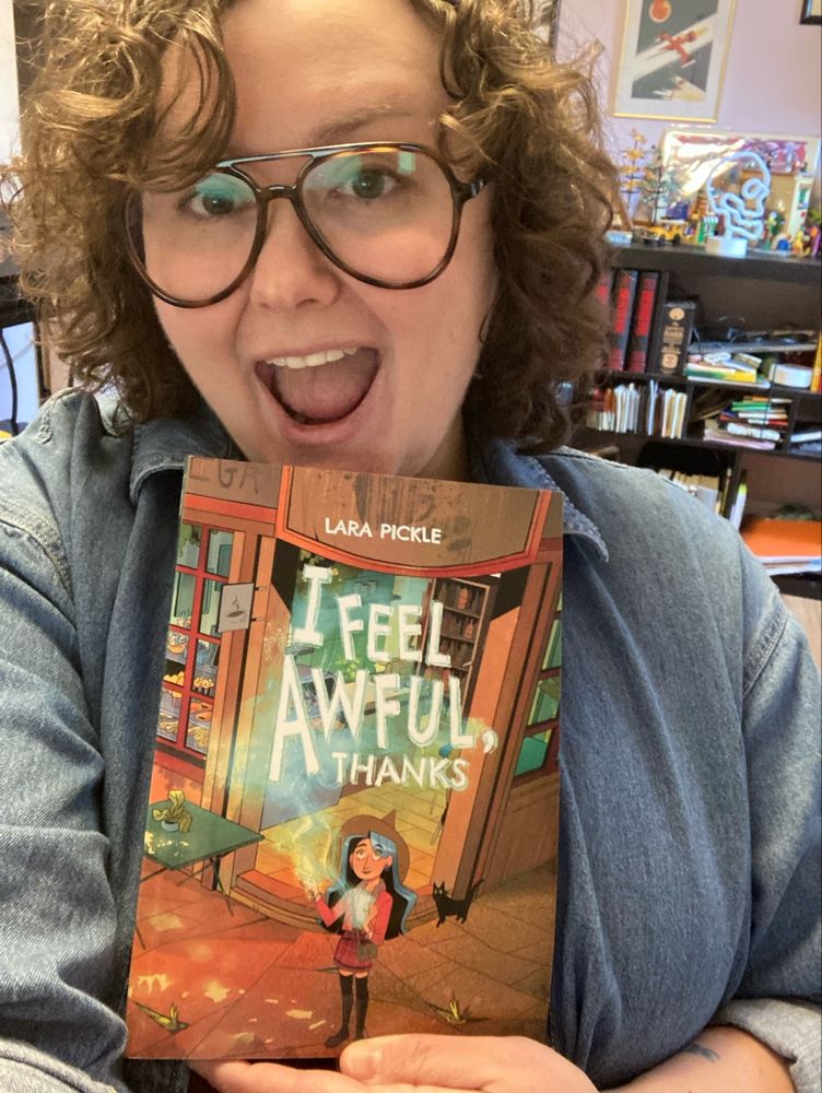 A woman with a big smile holds a copy of I Feel Awful, Thanks, by Lara Pickle.
