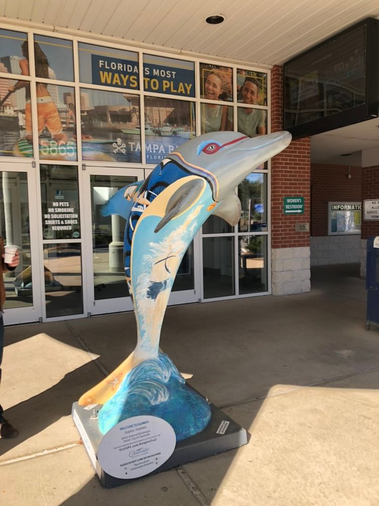 A statue of a dolphin with paintings of athletes on it at the Florida welcome center on the Alabama border