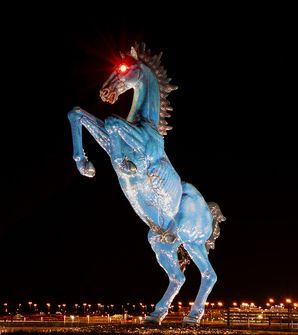 “Blue Mustang” sculpture that sits south of the Denver International Airport terminal, colloquially known as “Blucifer”. The blue-colored horse is rearing up aggressively on its hind legs and is notable for its bright red glowing eyes.