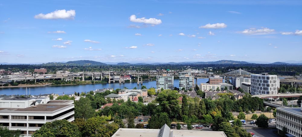 A photo facing east Portland, with the Willamette River dividing the photo. In the far distance is Mt. Hood