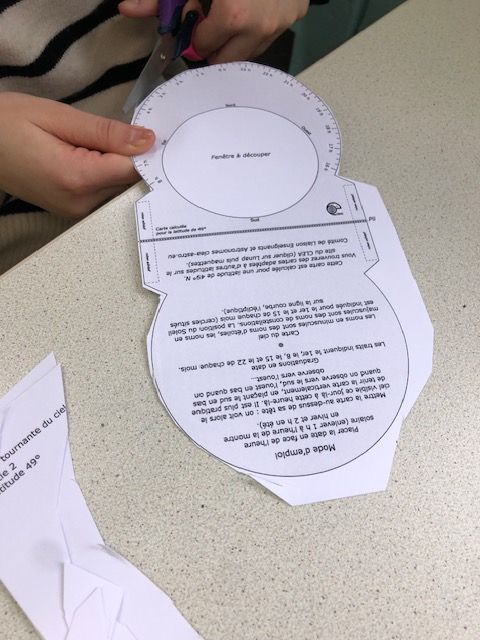 Mains en train de découper une figure imprimée sur papier blanc.