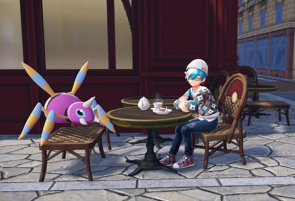 Nicks character in pokemon legends za a shaggy blue haired kid in a colorful sweater smiles at the camera with a shiny ariados.