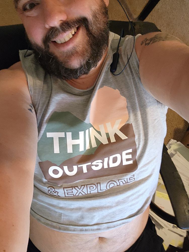 Nick in a grey "think outside and explore" cropped tank.