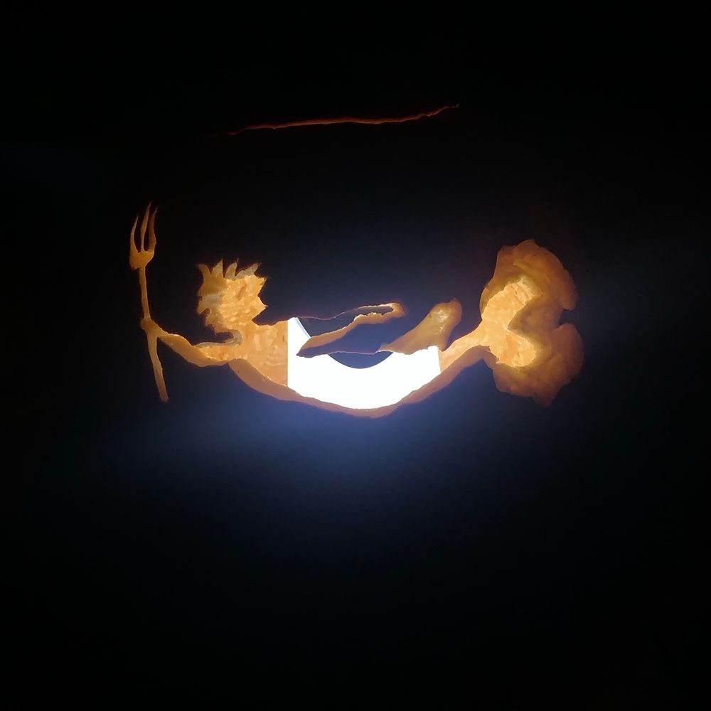A jack-o’-lantern carved with a merperson holding a trident 