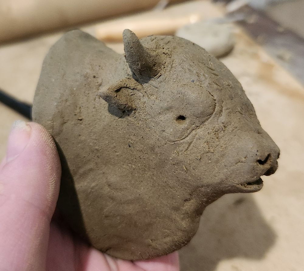 A clay sculpture bust of a bellowing bison