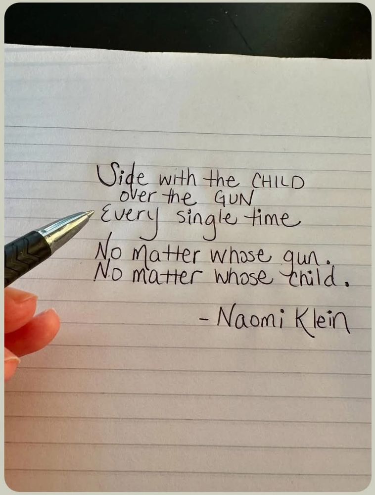 a photo of a hand holding a pen next to the hand-written text:
"Side with the child
over the gun
every single time.
No matter whose gun.
No matter whose child.
- Naomi Klein"