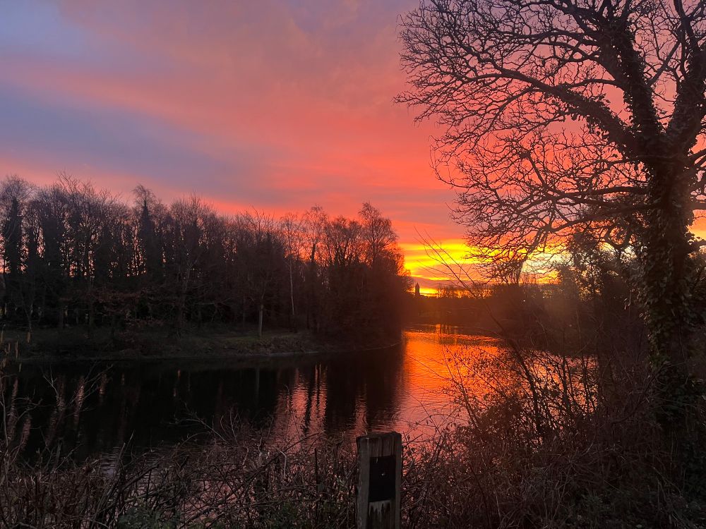 Sunrise reflecting off the water in Victoria Park, with St Marks Church spire in the distance. 