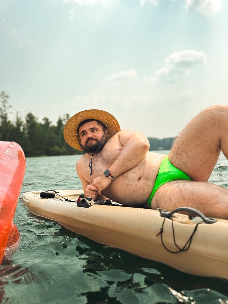 bear laying on paddle board with a speedo