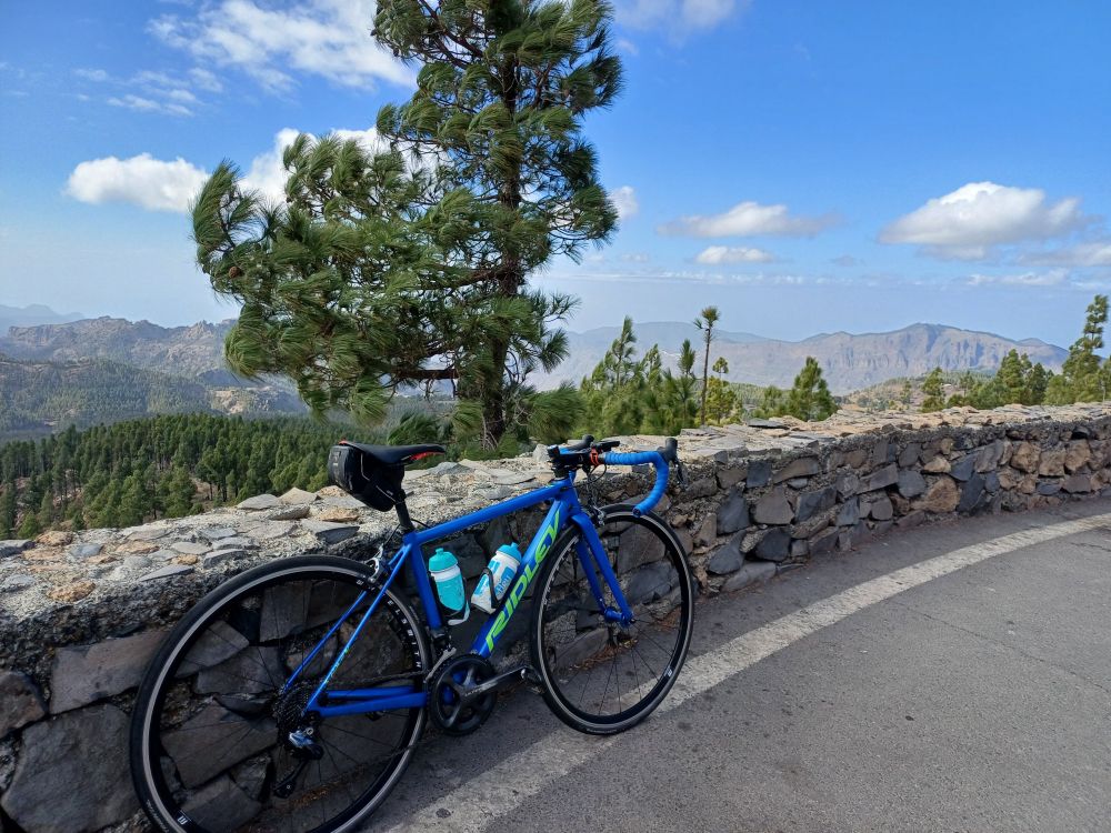 Blue bicycle against wall looking out from summit of Pico de las Nieves 