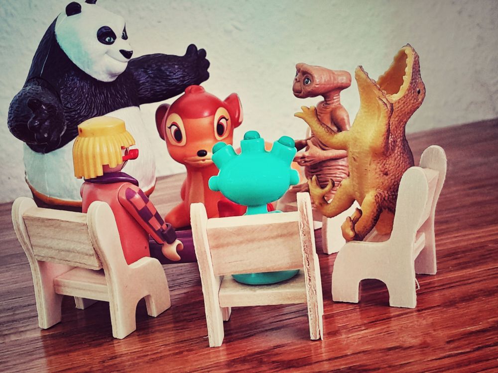 6 Spielzeugfiguren in einem Stuhlkreis 