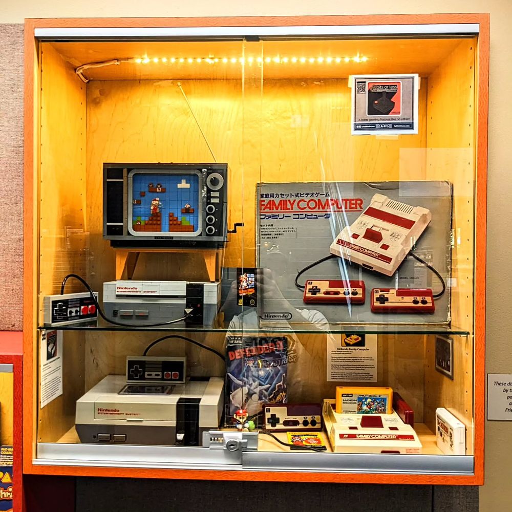The next case has an NES Console and controller, a Famicom console and controller, a box for the Famicom, and a model of an NES console and TV set built from Lego.