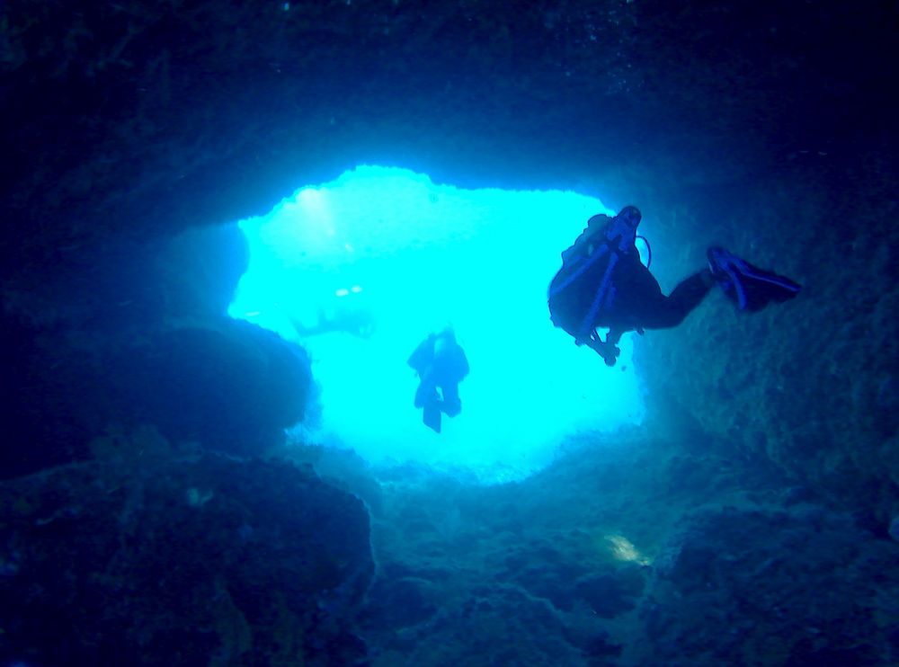 2 plongeurs sortent d'une grotte sous marine. 