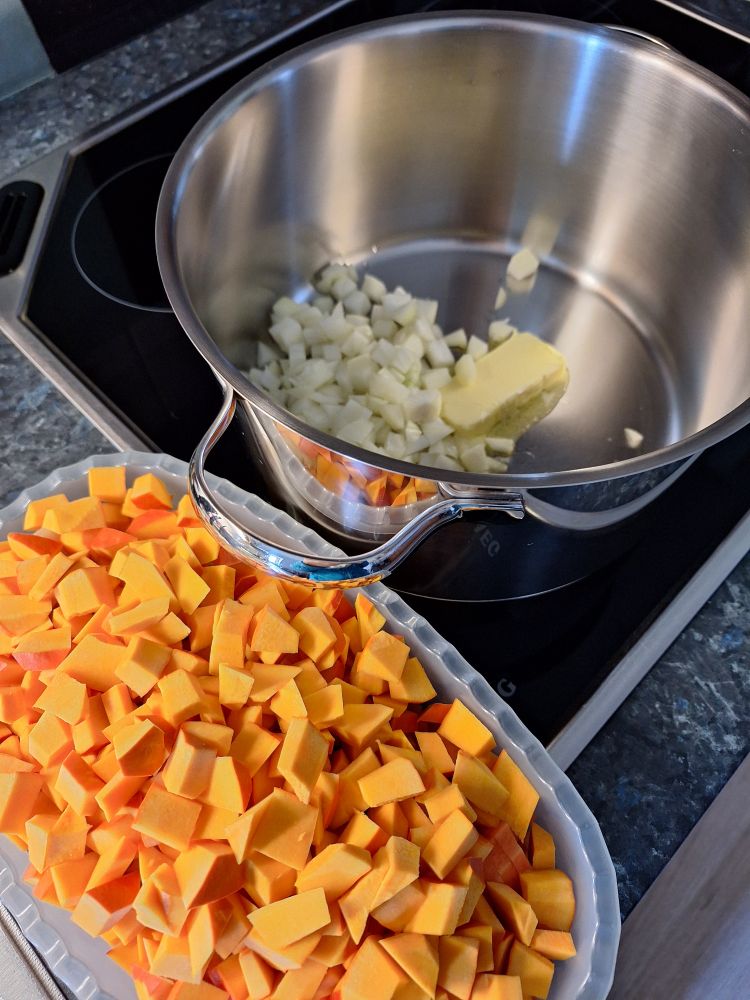Topf mit Zwiebeln und Butter, geschnittener Kürbis