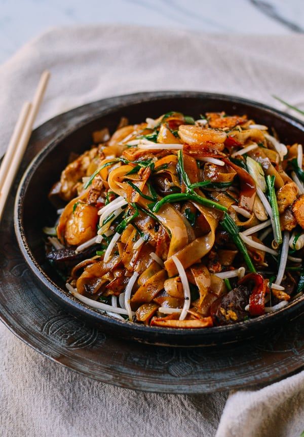 A bowl of ribbon noodles (rice) stir fried with a bunch of stuff including shrimp, chicken, egg, scallions, crunchy bean sprouts, soy sauce, and more. https://thewoksoflife.com/char-kway-teow/