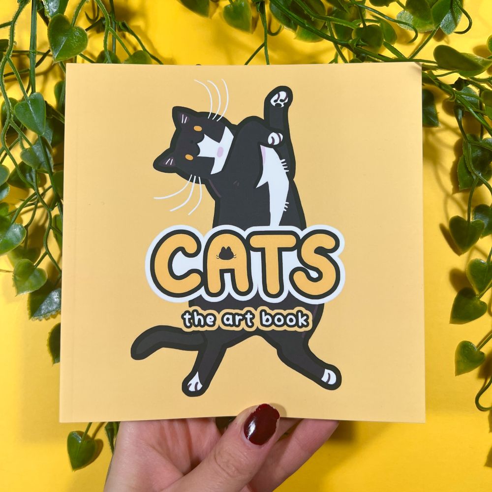 the cover of the book - it's yellow with a tuxedo cat cartoon and reads "cats - the art book"