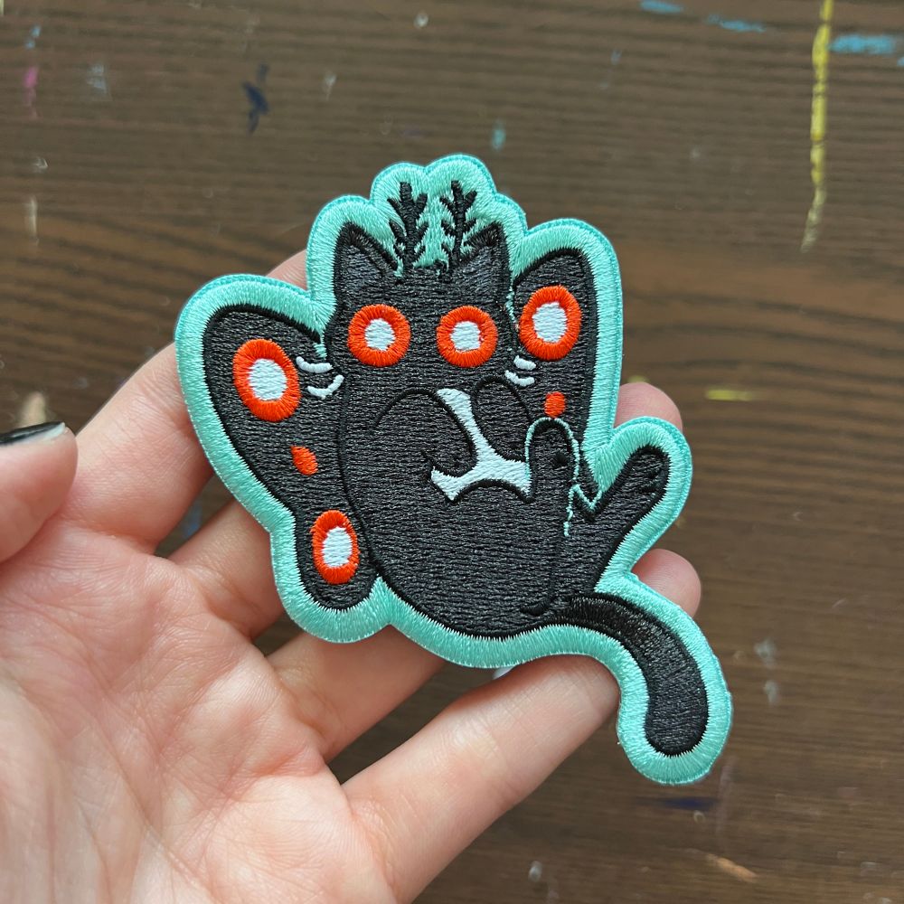 It’s an embroidered patch that looks like a mothman, but as a cat! Or maybe I should say a cat, that looks like mothman!