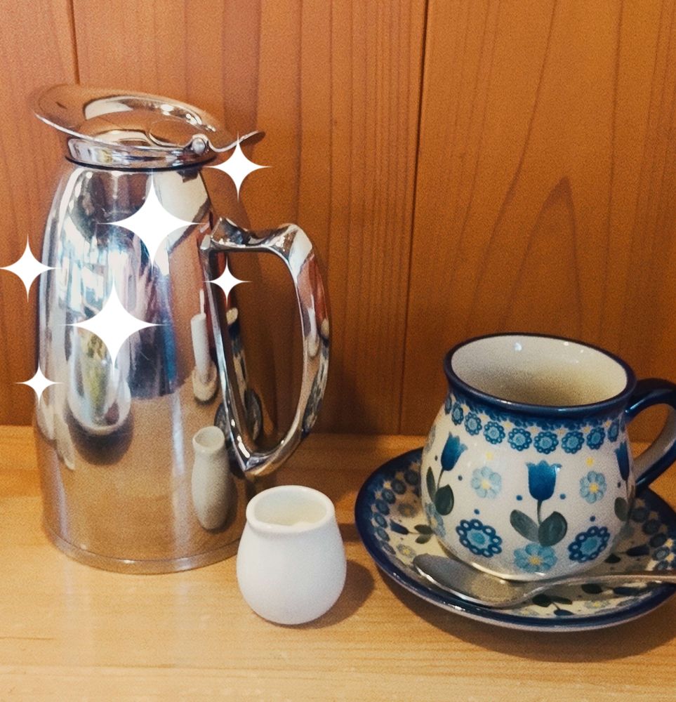 銀色の大きなコーヒーポットと素朴な花柄のコーヒーカップ