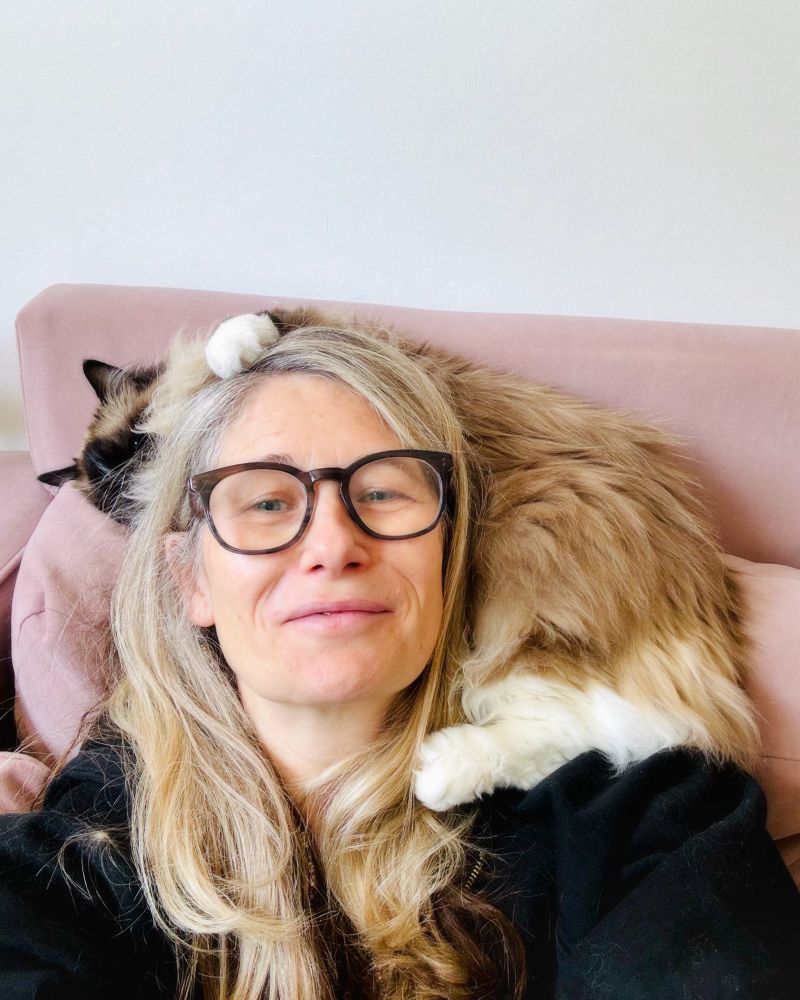 I am in glasses smiling at the camera  with my rag doll cat Bob curled around my neck, white paw on my head.