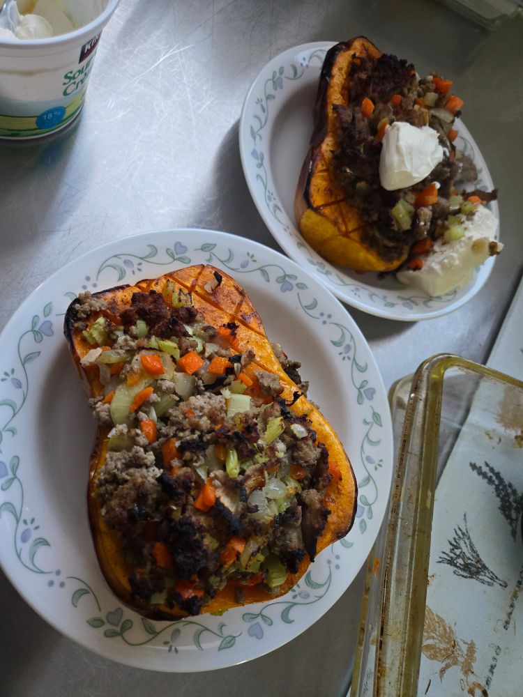 Roasted homegrown butternut squash stuffed with ground pork, carrots, onions, and celery. Seasoned with thyme and sage
Ready to eat on Corelle "Country Cottage" soup plates.  One serving with sour cream.