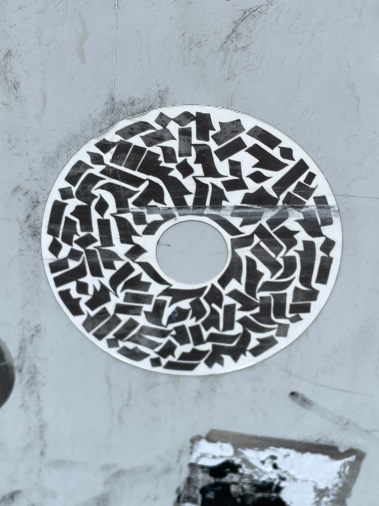 Donut-shaped sticker with thick black calligraphy strokes.