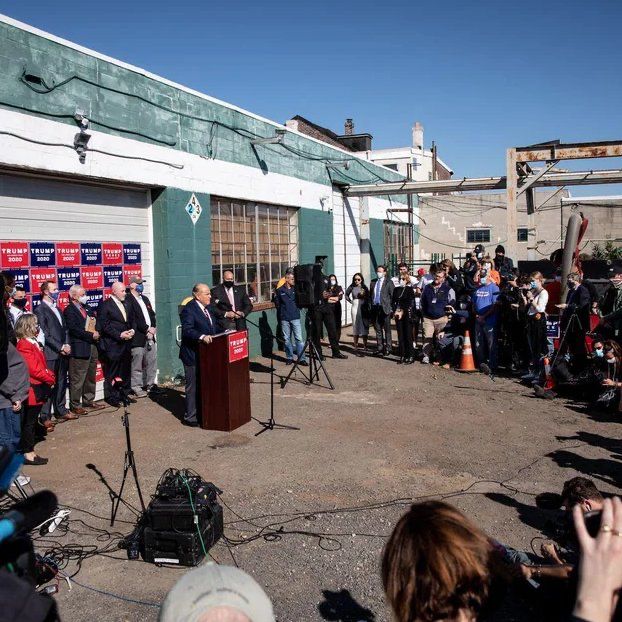 Pressekonferenz des Trump-Teams auf dem Firmenparkplatz des "Four Seasons Total Landscaping" Man sieht ein heruntergekommenes Firmengebäude, Trump Vertreter und Journalisten 