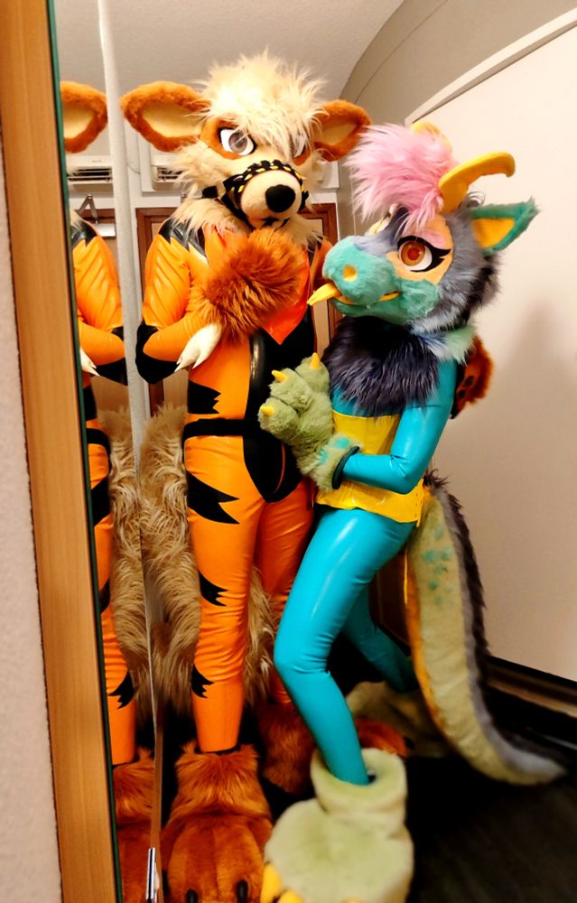 Furries in latex. One on the left is an arcanine/orange canine with black stripes, one on the right is a light blue dragon with a yellow corset and pastel green feet/paws