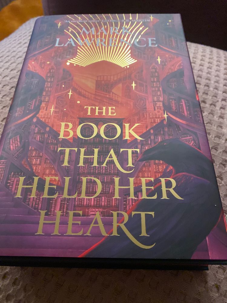 Image of a book cover: the book that held her heart by mark lawrence. 