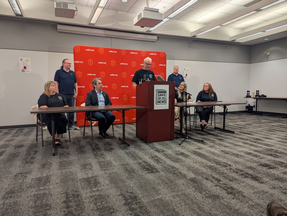 several people at a press conference in front of a Uniform background