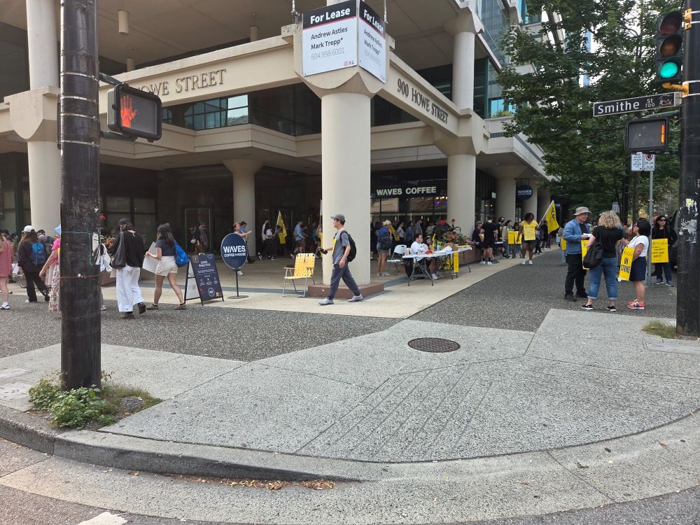 members of a union holding yellow signs, marching at the corner of a building