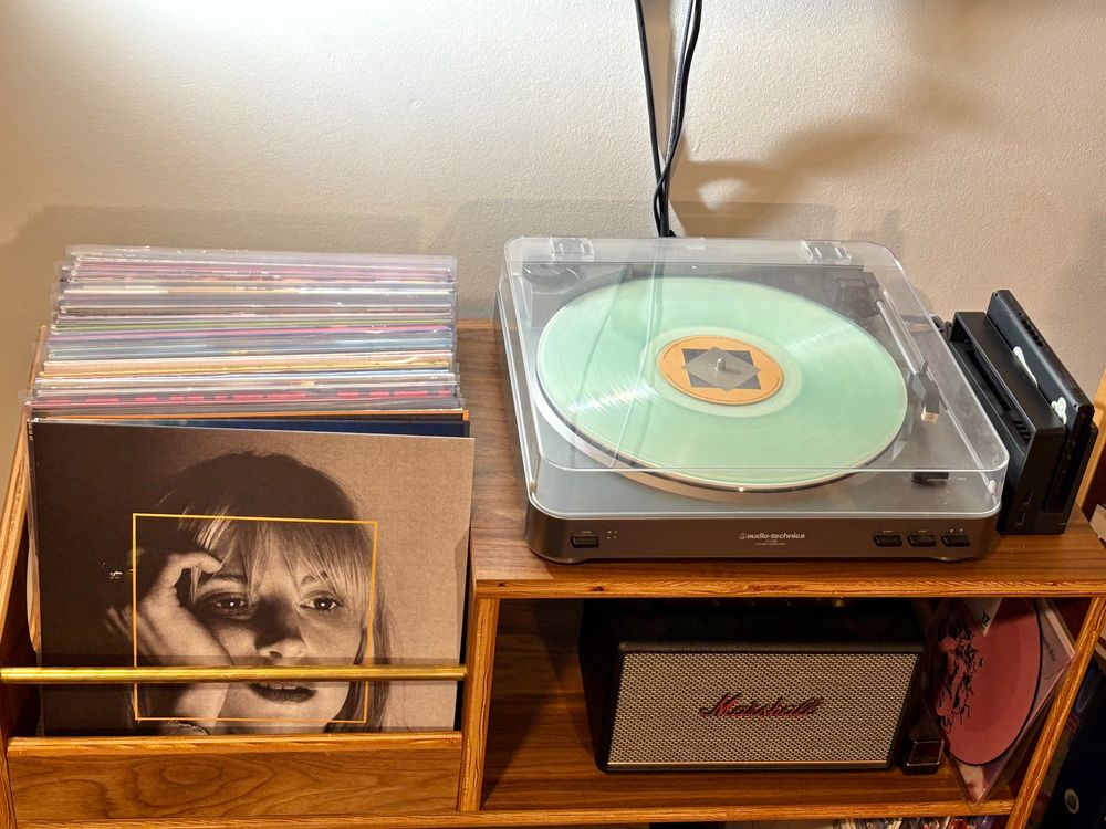 My record cabinet with a sea-foam green record on the turntable. At the front of the stack of records is the album's jacket, which features Hayley Williams in black and white.