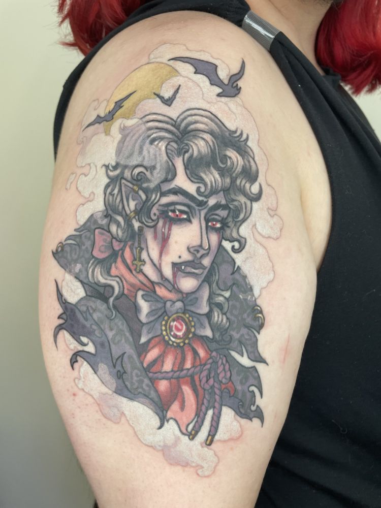 A portrait tattoo featuring a vampire in tattered but regal clothing, blood dripping from his eyes and mouth and a lil fang peeking out. He's surrounded by fog, and a full moon peeks through the fog, with a few bats flying by.