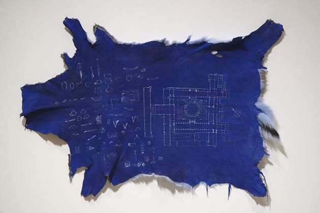 An animal hide covered in blue felt with a floor plan of a museum drawn on it
