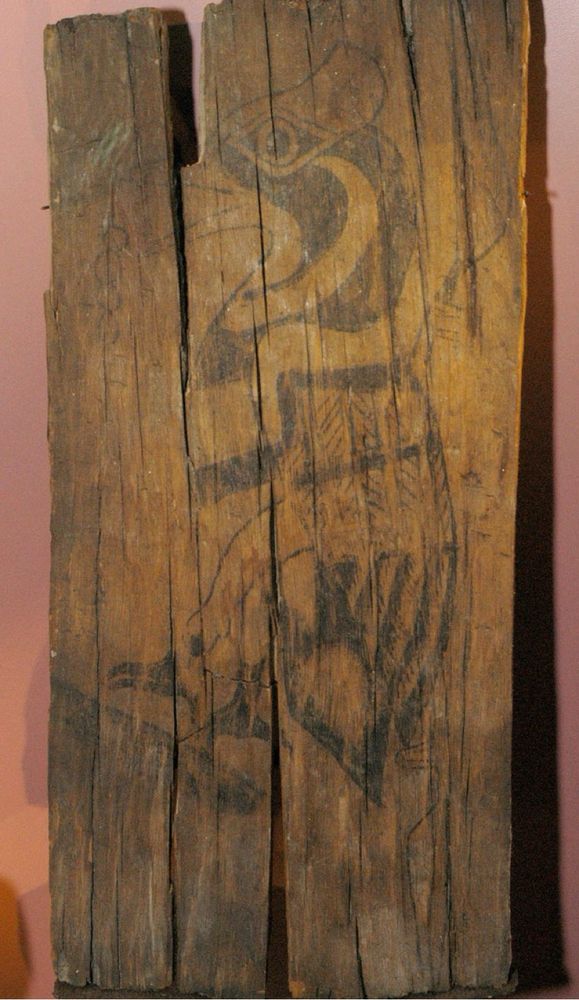 A faded drawing of a woodpecker on an old plank of wood