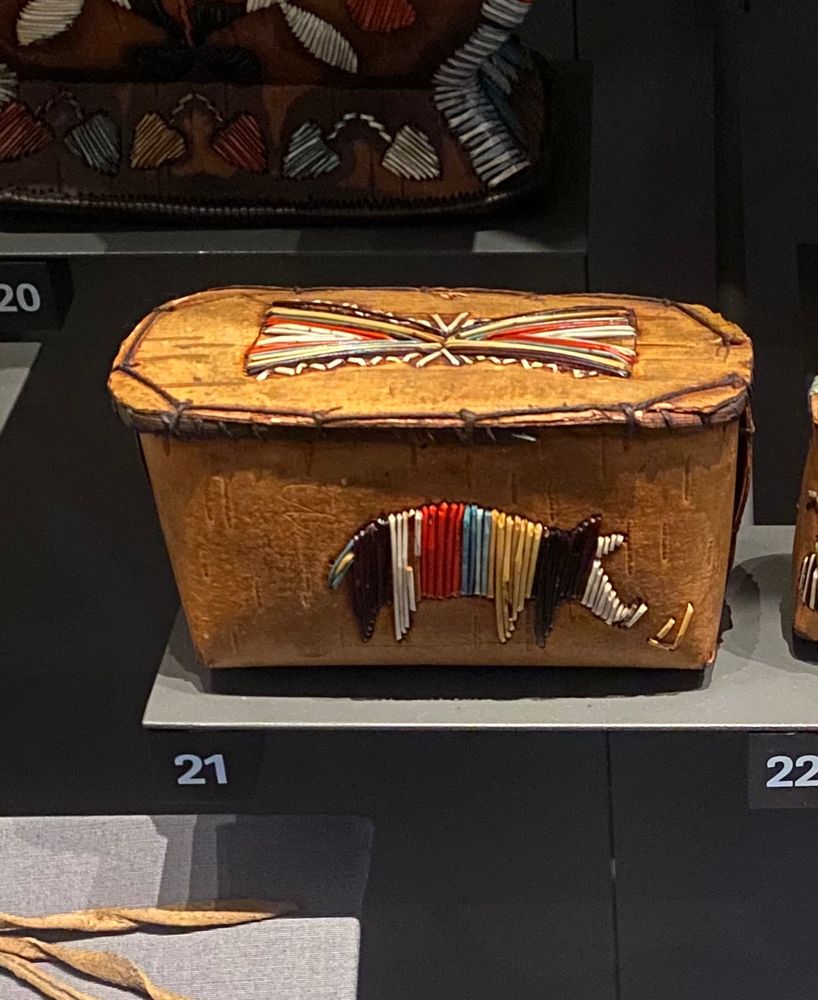 A box made of bark featuring a multicoloured pig made of dyed quills.