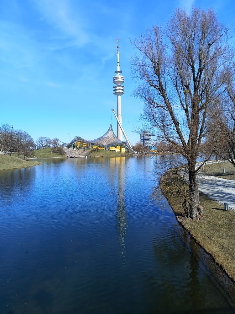In einem See spiegeln sich der blaue Himmel und der Olympiaturm