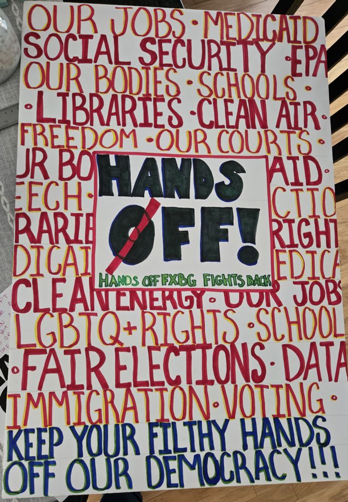 Handmade poster for HANDS OFF rally on April 5th. Poster has HANDS OFF in center in black with HANDS OFF FXBG FIGHTS BACK in green. red words repeating in background say: OUR JOBS * MEDICAID * SOCIAL SECURITY * EPA * OUR BODIES * SCHOOLS * LIBRARIES * CLEAN AIR * FREEDOM * OUR COURTS * CLAN ENERGY * OUR JOBS * LGBTQ+ RIGHTS * SCHOOLS * FAIR ELECTIONS * DATA * IMMIGRATION * VOTING * at bottom blue words say KEEP YOUR FILTHY HANDS OFF OUR DEMOCRACY