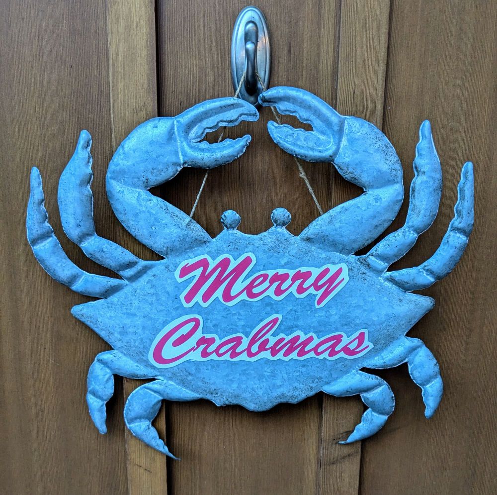 A galvanized steel door hanging in the shape of a crab with the words "Merry Crabmas" magnetized to its shell.