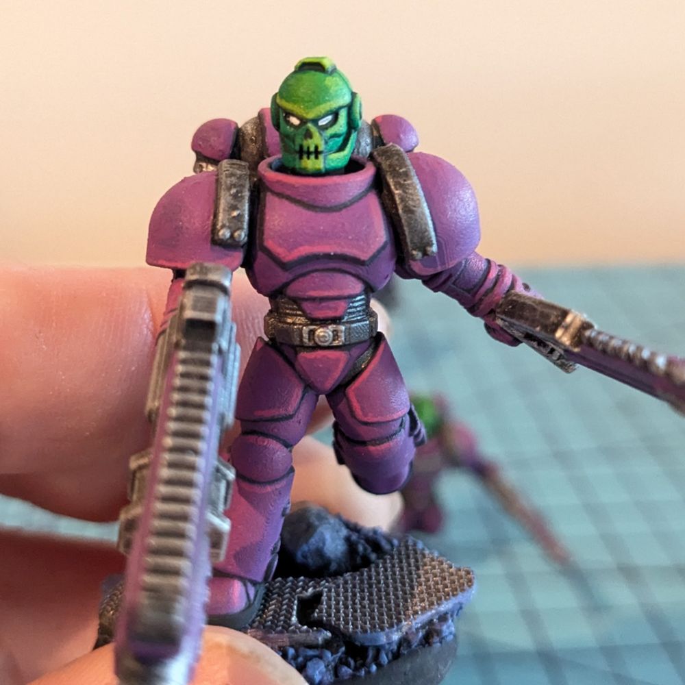 A scifi warrior tabletop miniature in power armor with a skull face helmet. 