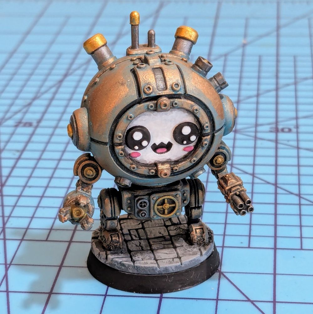 A steampunk mech miniature painted to look like oxidized copper. The mech has a smiling face 