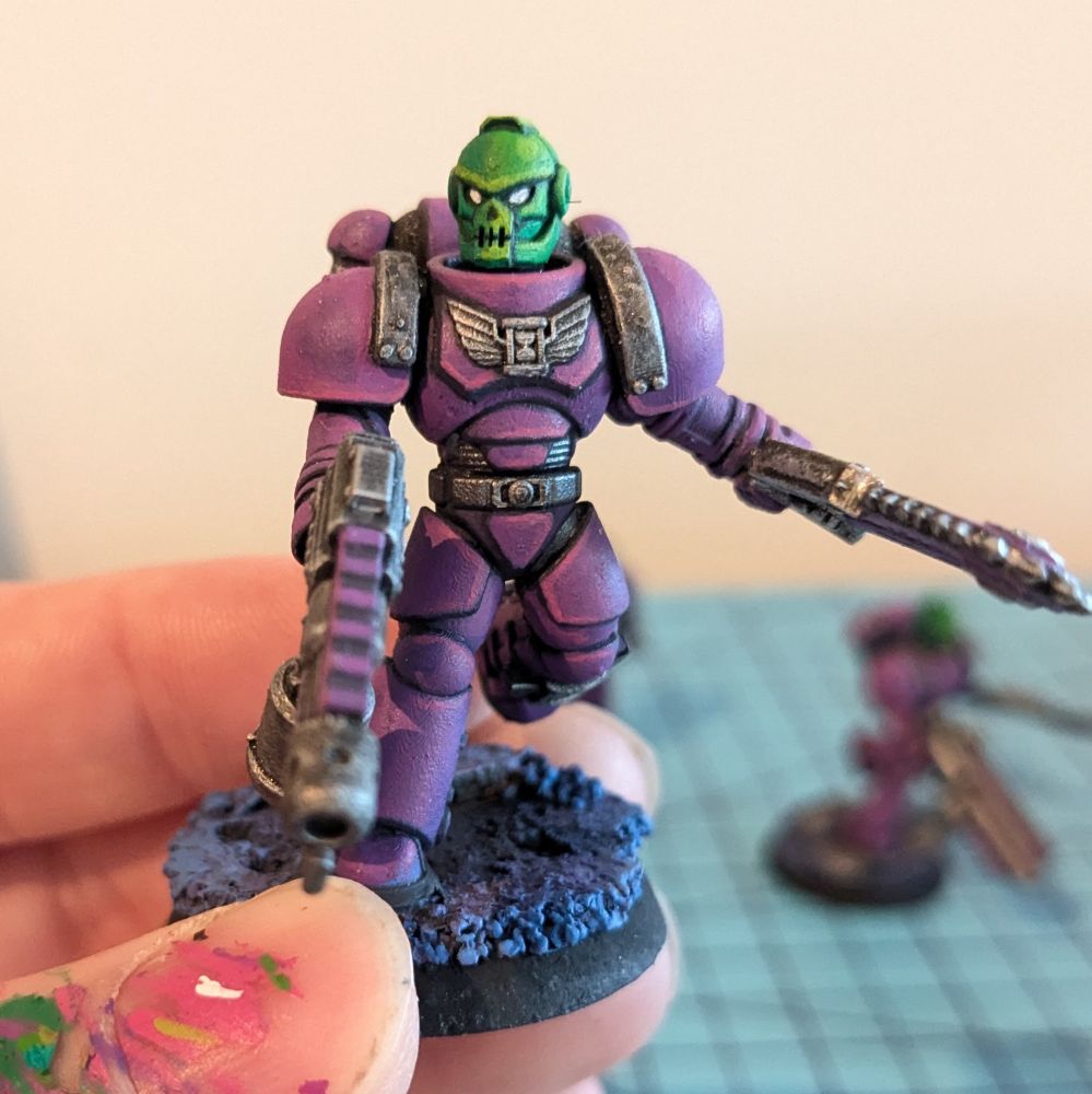 A scifi warrior tabletop miniature in power armor with a skull face helmet. 