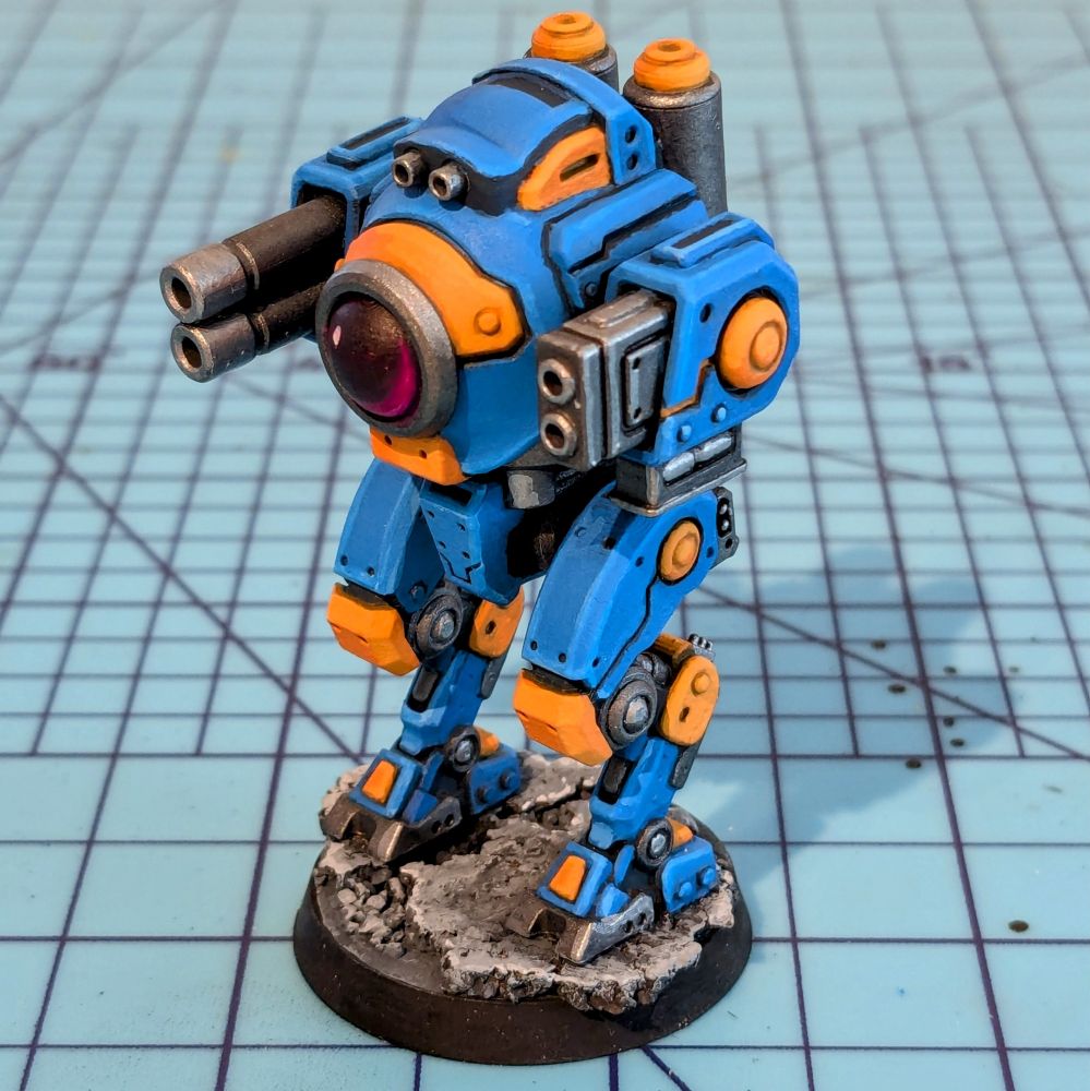 A toy of a long legged robot with a large lens eye. The robot has cannons for arms 